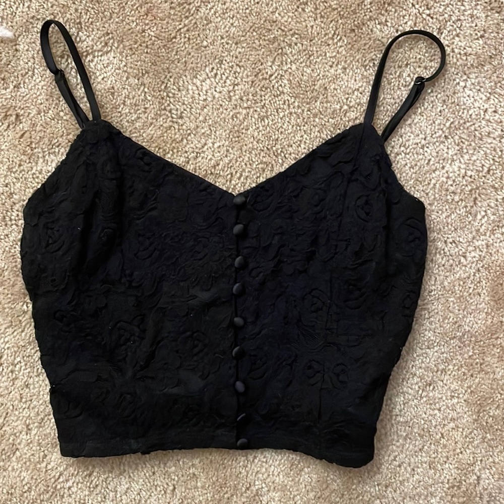 This is a black crop top with lace and buttons down the middle.